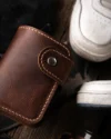 Yakın çekimde parlayan pirinç nikel çıtçıt detayı ile taba hakiki deri cüzdanın kaliteli işçiliği, Dogaartcraft el yapımı